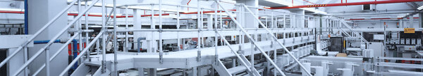 Lange Arbeitsbühne mit Treppenaufgang entlang einer Produktionsanlage